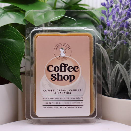 Wax melt packaging labeled 'Coffee Shop' with plants in the background