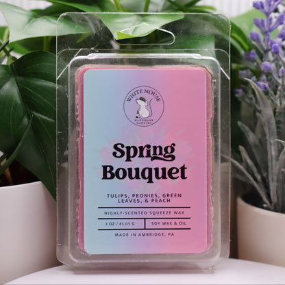 Packaged wax melt with 'Spring Bouquet' label in front of plants